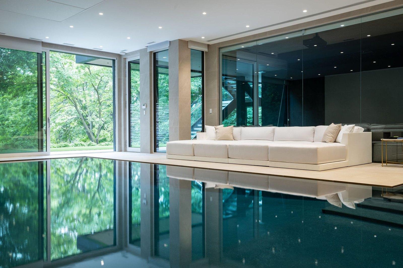 An indoor Betz pool in a glass room, still enough to mirror the trees outside
